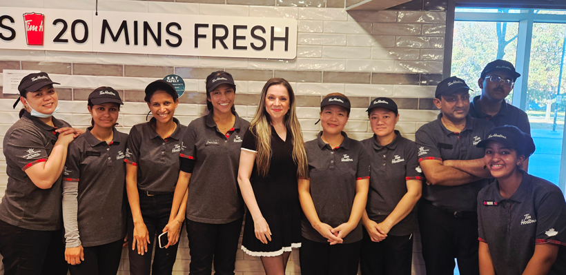 Members working for Compass Group at a Tim Hortons at York University pose for a photo in their workplace.